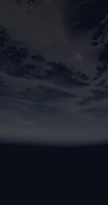 A partially illuminated Earth with visible continents and cloud cover.