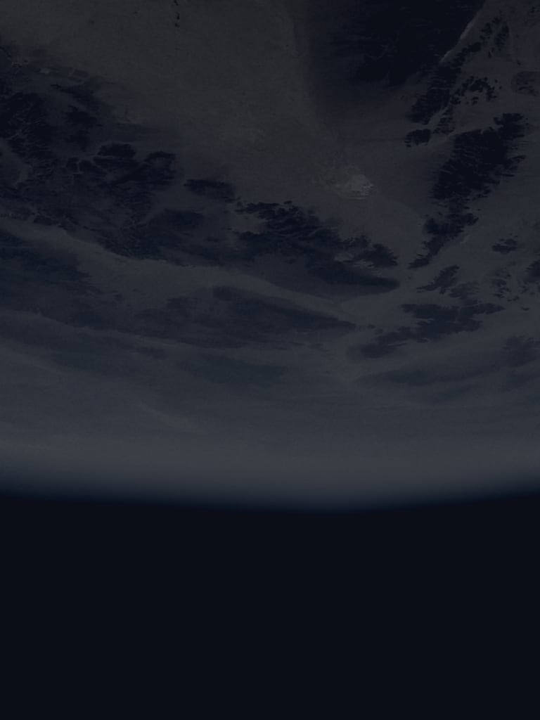 A partially illuminated Earth with visible continents and cloud cover.