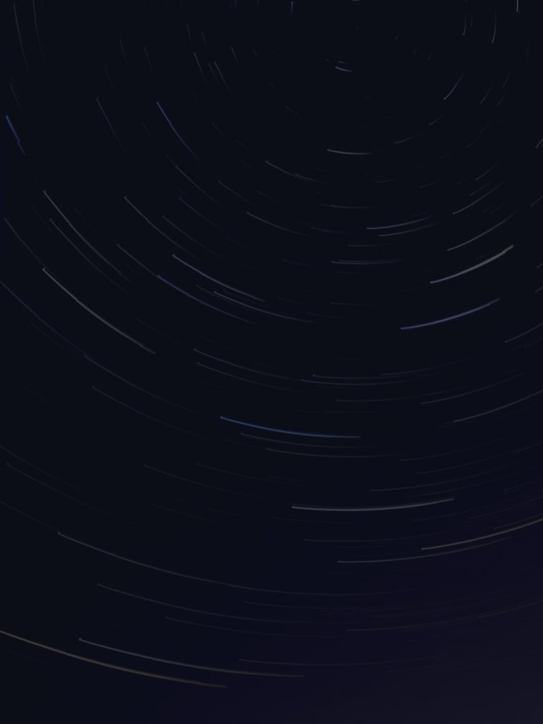 Star trails dance across the midnight canvas, leaving ethereal arcs of light.